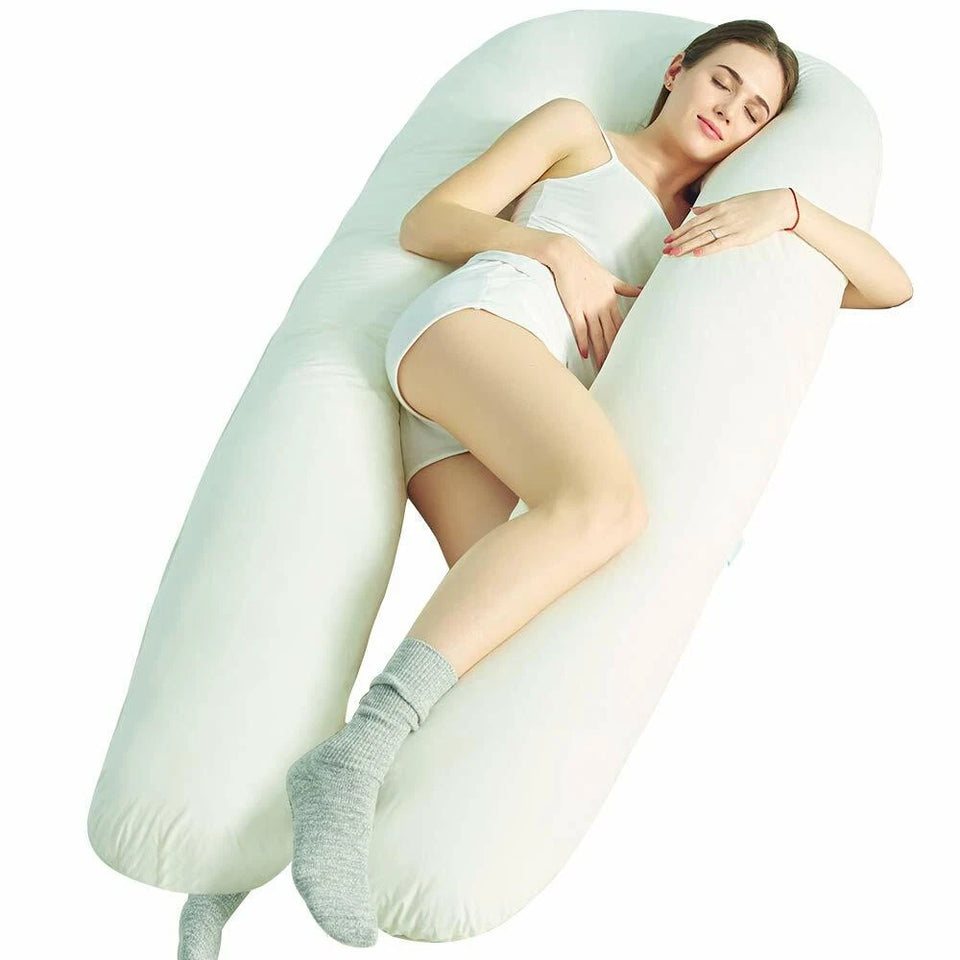 Woman lying on her side in a long white U shaped pregnancy pillow