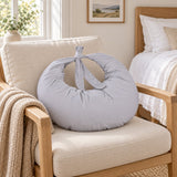 Grey tie-top breastfeeding pillow on an armchair in a bright bedroom (AI-generated image)