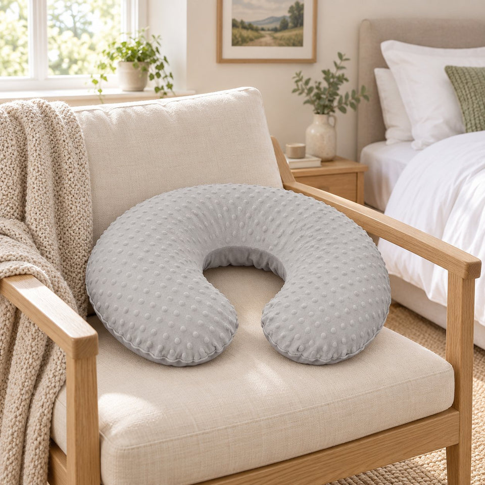 Grey nursing pillow with dimple cover on an armchair in a bright bedroom (AI-generated image)