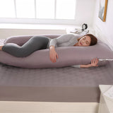Mauve U shaped pregnancy pillow supporting back, bump and legs on a double bed