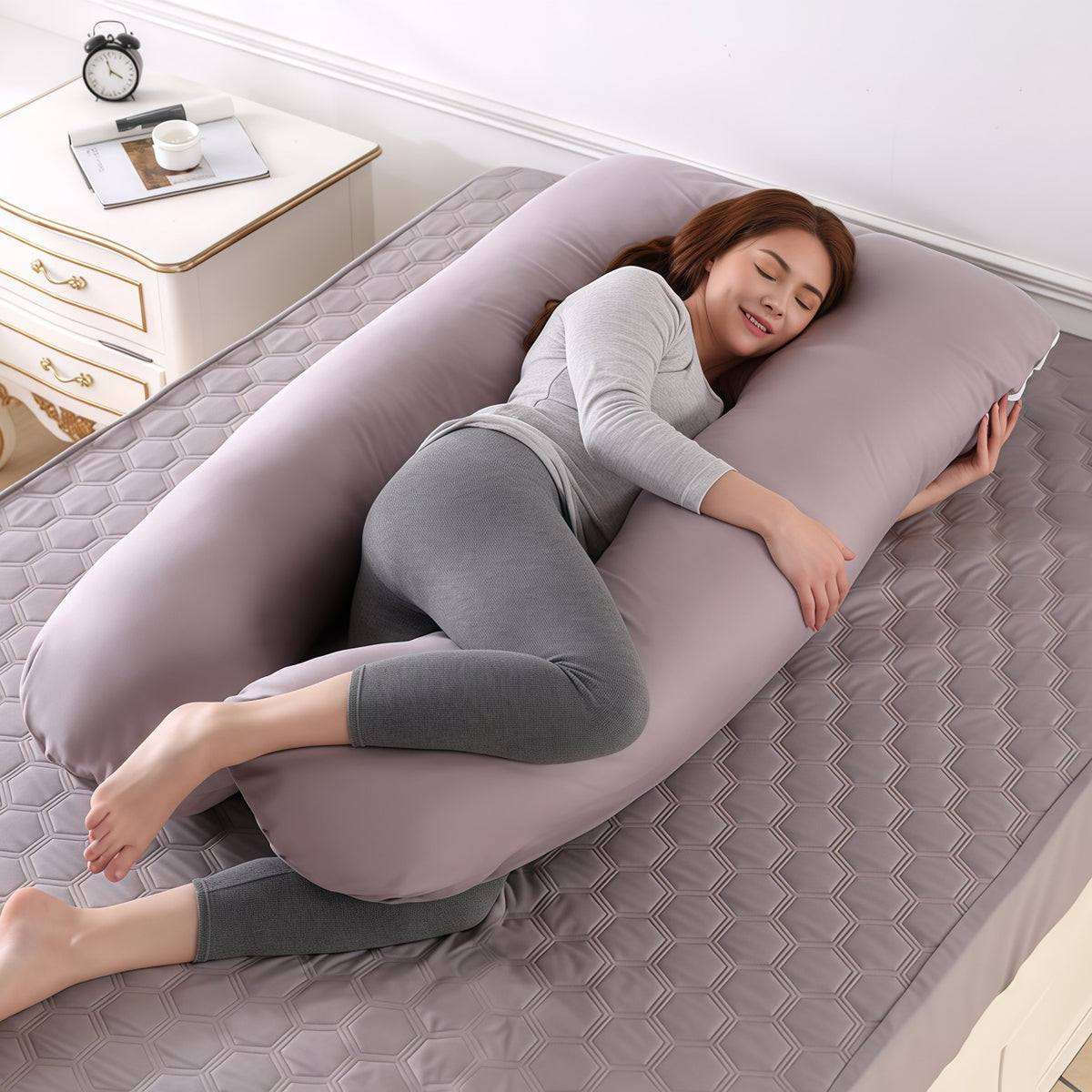 Pregnant woman side sleeping with a mauve U shaped pregnancy pillow
