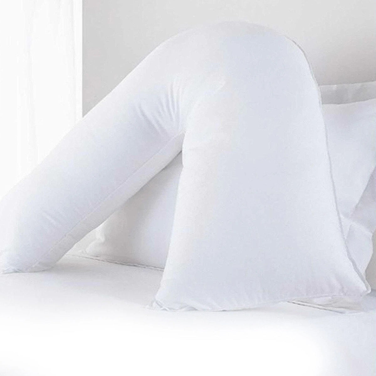 White V shaped pregnancy pillow on a bed